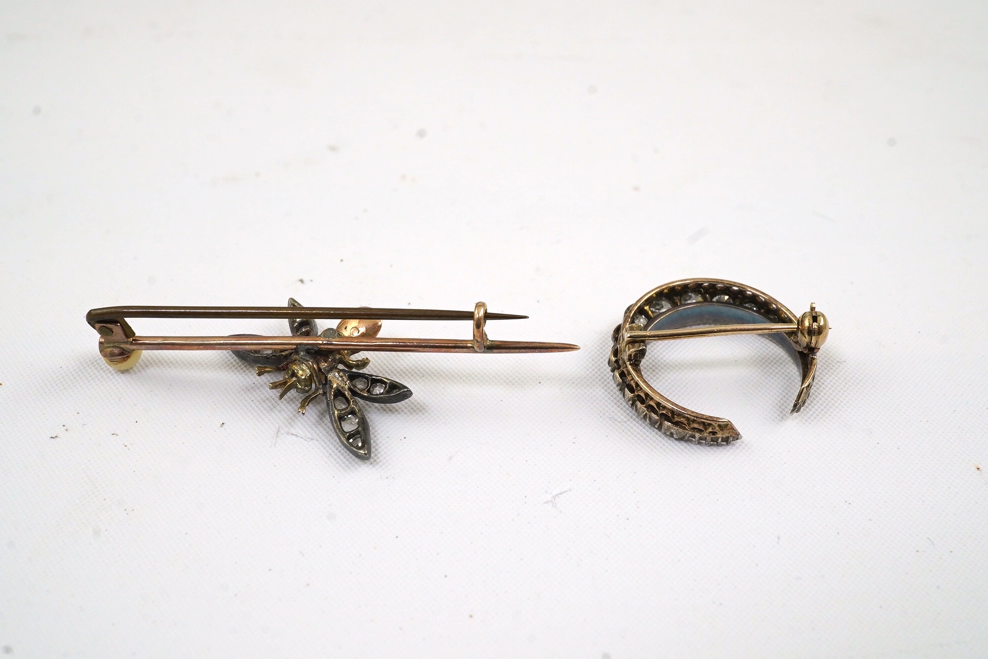 An Edwardian gold and graduated diamond set crescent brooch, 20mm, together with a similar gold, seed pearl diamond and cabochon set bug bar brooch (stone missing), 47mm